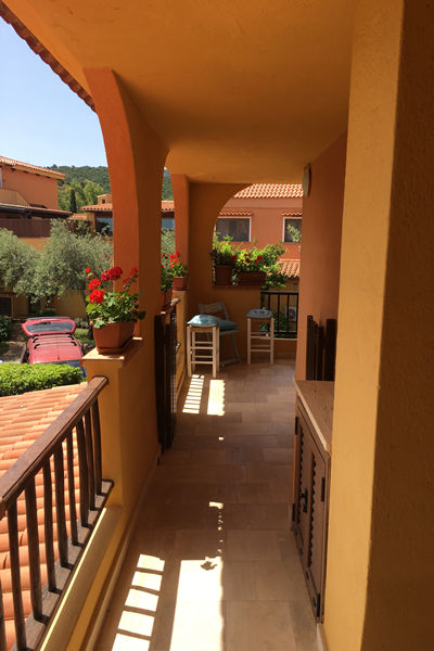 a walkway with balustrades, tubs of flowers with sun streaming onto the stone tiled floor